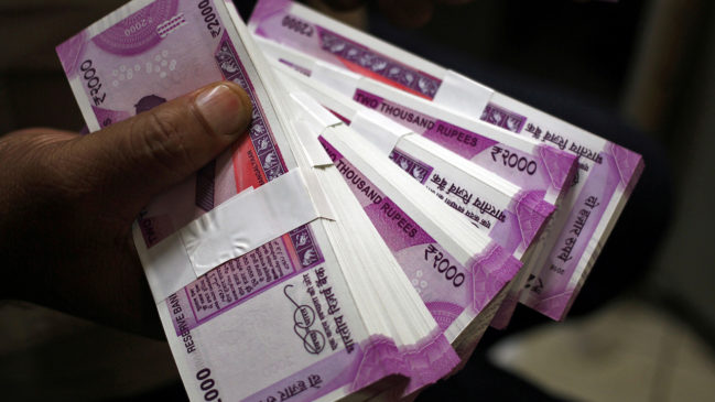 FILE PHOTO: A cashier displays the new 2000 Indian rupee banknotes inside a bank in Jammu